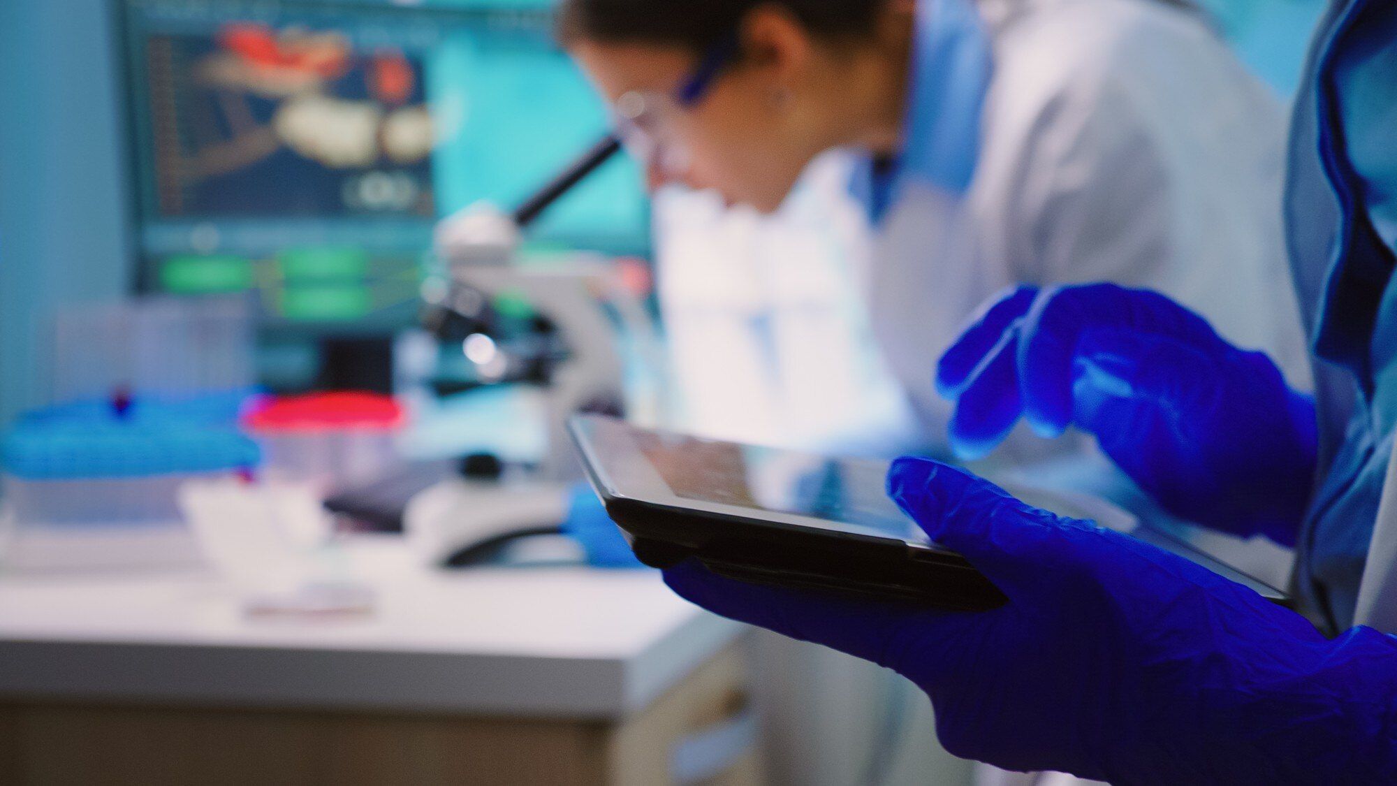 close-up-scientist-writing-tablet-while-team-biologists-doing-biological-researches-microscope-backgorund-late-night_482257.jpg